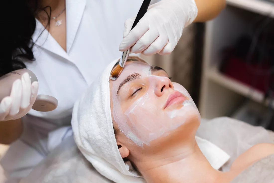 beautician-with-brush-applies-white-moisturizing-mask-face-young-girl-client-spa-beauty-salon