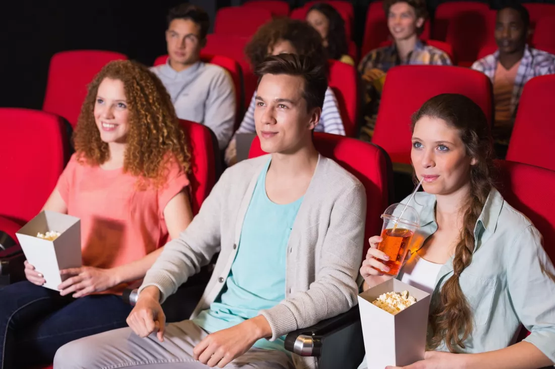 Studenci oglądają film na dużym ekranie w niewielkiej sali kinowej.