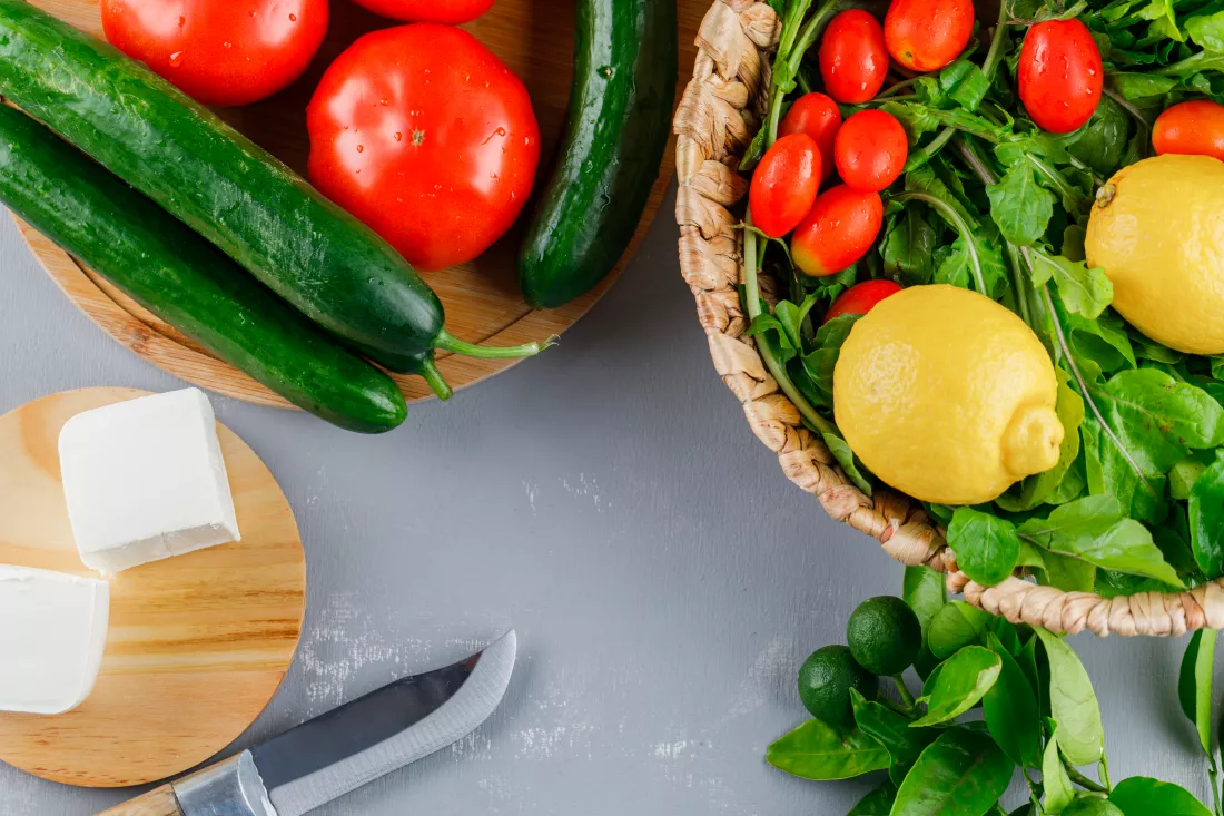 set-knife-lemon-cucumber-cheese-greens-tomatoes-cutting-board-gray-surface