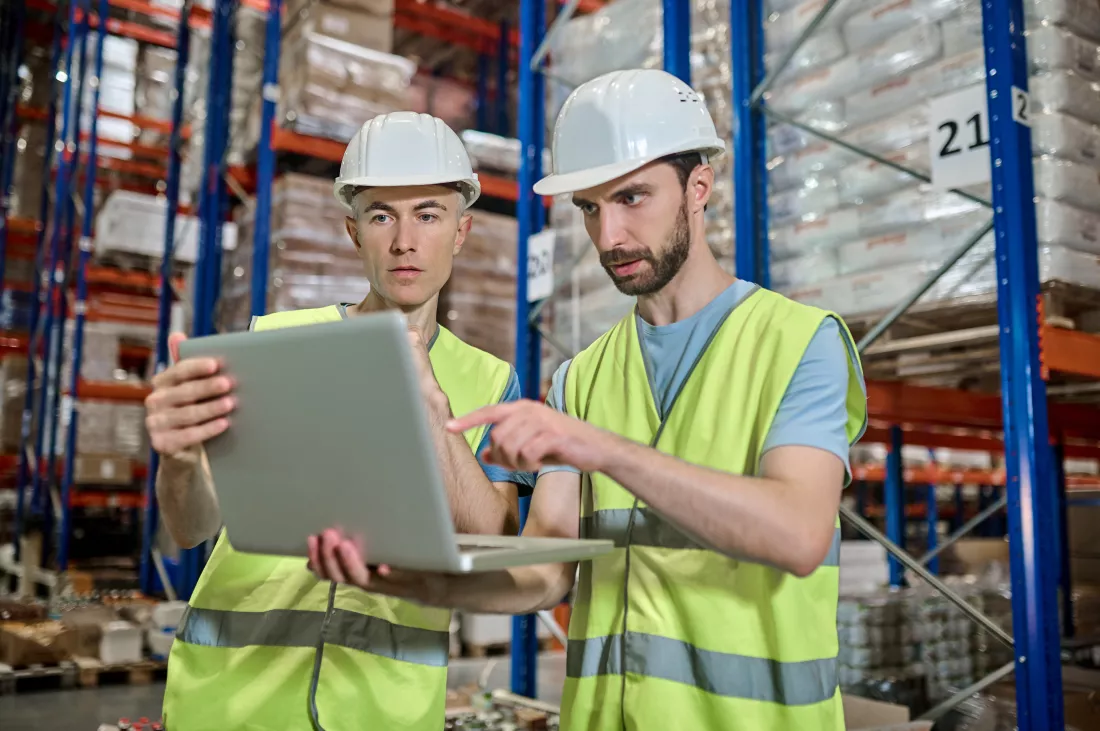 two-men-looking-laptop-deciding-work-question-warehouse